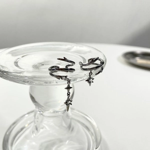 Close-up of black thorn branch earrings with star pendants on glassware