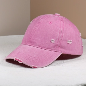 Detail of pink washed cotton baseball cap with distressed rip and vintage frayed edge