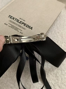 Close-up of black silk ribbon bow hair clip with silver spring mechanism for hair styling