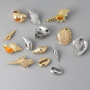 Assorted gold and silver sea shell pendants for DIY jewelry making on grey background