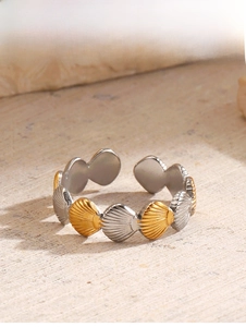 Detail of two-tone gold and silver shell-shaped overlapping band ring on wooden surface