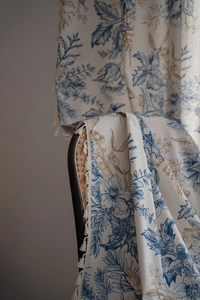 Detailed view of beige pine branch pattern curtain with fringe on a rattan chair