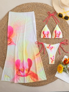 Flat lay of floral bikini three-piece set with mesh skirt and beach holiday accessories