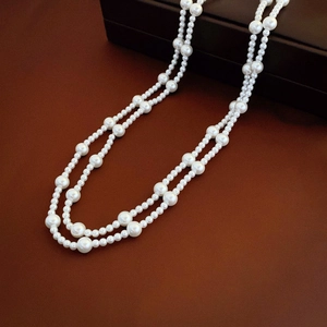 Elegant vintage long double-layer pearl necklace on a premium dark brown leather surface