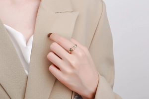 Detail shot of a golden heart gesture ring featuring a unique hands-holding-heart design