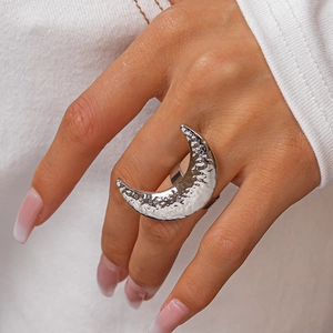 Detail of silver moon ring with hammered metal texture worn on a hand over white knitwear