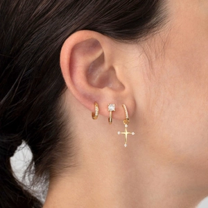 Close-up of gold U-shaped hoop earrings with cross pendants and zircon inlay on model