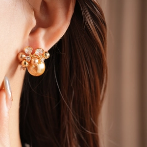 Detailed view of champagne pearl flower earrings with sparkling zircons worn by model