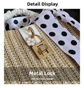 Detail of golden metal clasp with white floral charm on woven straw apple bag