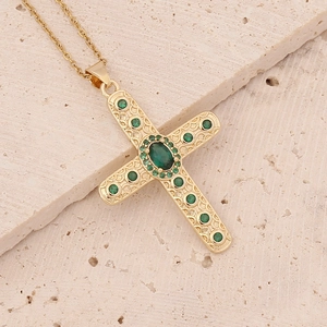 18K gold plated copper cross pendant necklace with green zircon stones on stone surface