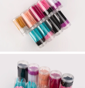 Close-up of colorful disposable eyelash brushes organized in clear plastic tube containers