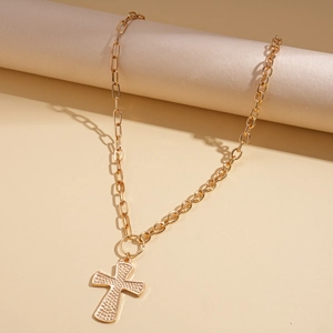Dettaglio della collana con ciondolo a croce dorata con superficie testurizzata e maglie miste