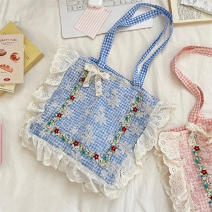 Close-up of blue plaid canvas tote featuring floral embroidery and white lace edges