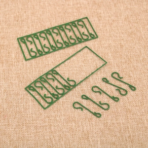 Close-up of green S-shaped Christmas ornament hooks on a natural burlap background