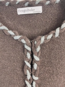 Gros plan sur la veste en maille marron avec bordure tissée gris bleu et détails de luxe