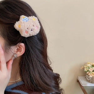 Detail of cute plush bear hair claw clip with blue party hat worn on hair