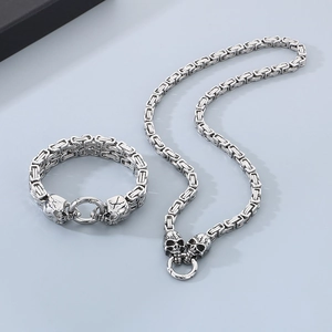 Close-up of silver Byzantine chain necklace and bracelet set with skull head clasps