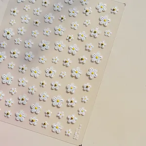 Detailed macro view of 3D white daisy nail art stickers with golden crystal centers