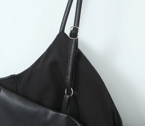 Detalle de tirantes ajustables de cuero sintético con anillos metálicos plateados en vestido negro