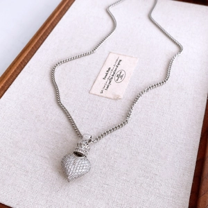 Macro shot of silver heart crown pendant with cubic zirconia on a chic curb chain