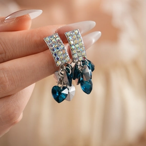 Close-up of heart tassel drop earrings with blue crystals and silver needles finish