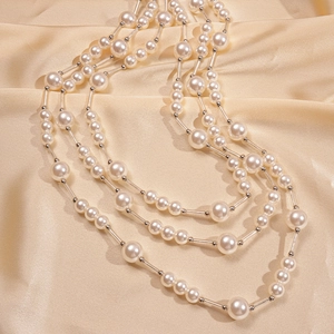 Détail d'un collier de perles à trois rangs avec accents argentés sur fond satiné