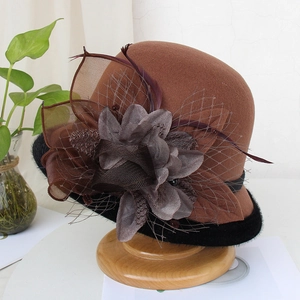Detail of vintage brown wool felt hat featuring mesh veil, feathers, and a large flower decoration