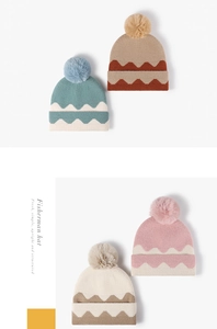 Detailed knit texture of wave pattern beanie featuring a fluffy pom-pom and folded cuff