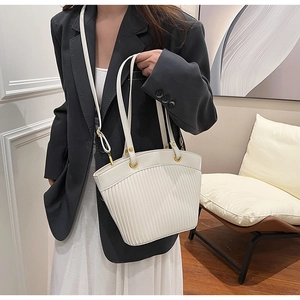 Detail of white striped tote bag with gold hardware ring and adjustable crossbody strap