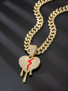 Detail of gold Cuban link chain with iced out broken heart and blood drop pendant