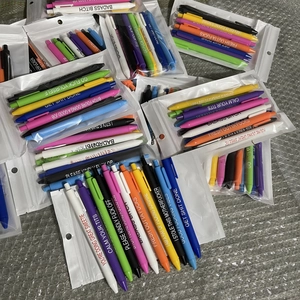 Detailed view of colorful novelty pens with funny slogans in clear plastic zipper pouches