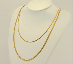 Detailed view of layered golden stainless steel snake chain necklace on white display