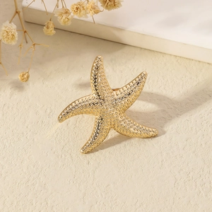 Golden starfish open ring with relief texture on cream textured background