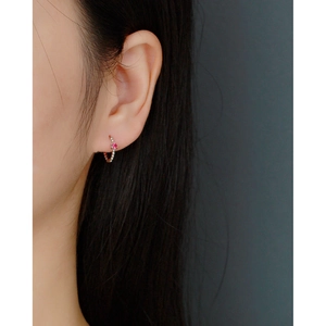 Close-up of S925 sterling silver huggie earring with beaded edge and pink stone detail