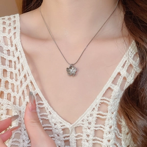 Close-up of a silver flower pendant necklace with white pearl on a sleek snake chain