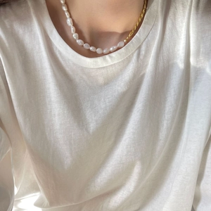 Minimalist 925 silver necklace with baroque pearls and golden chain on a model's neck