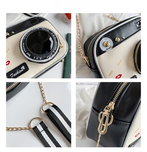 Detail of creative camera-shaped crossbody bag featuring a 3D lens and striped strap