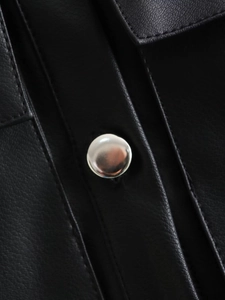 Detail of black leather vest featuring textured grain and polished silver metal button