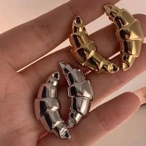 Close-up of gold and silver croissant style earrings with high polished pleated details