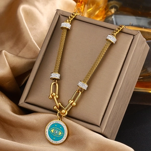 Vue macro du collier doré à maillons U avec œil en émail bleu et cristaux étincelants