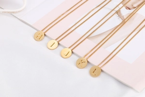 Close-up of gold disc initial pendants from H to L on polished cable chain necklace