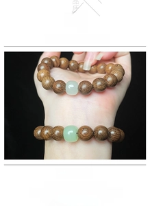 Gros plan sur un bracelet en bois de santal avec perle centrale en jade vert