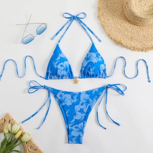 Flat lay of royal blue floral bikini set with gold flower pendant and beach accessories