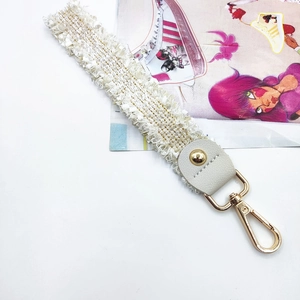 Detail of off-white lace fringe strap with white leather and gold metal lobster clasp