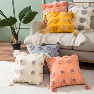 Close-up of tufted cushion covers with heart patterns and decorative tassels on a sofa