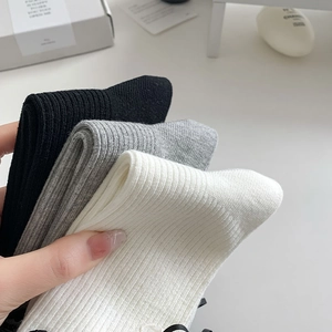 Three pairs of ribbed knit crew socks in black, light grey, and cream white colors