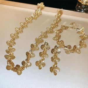 Detailed view of 3-piece gold jewelry set with flower-shaped necklace and bracelet charms