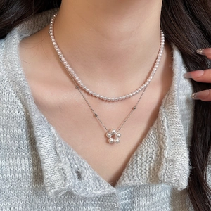 Detail of elegant double-layered pearl necklace with a delicate flower pendant on a model