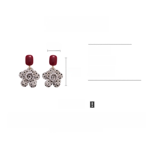 Detail view of acrylic floral drop earrings featuring retro polka dots and square studs
