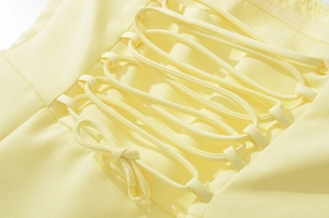 Dettaglio del corsetto stringato sulla schiena di un abito lungo giallo con spalle scoperte